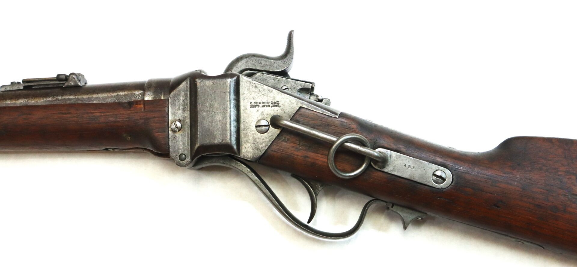 Side view of an antique lever-action rifle with a wooden stock and metal receiver, showing a prominent lever and ring on the side.