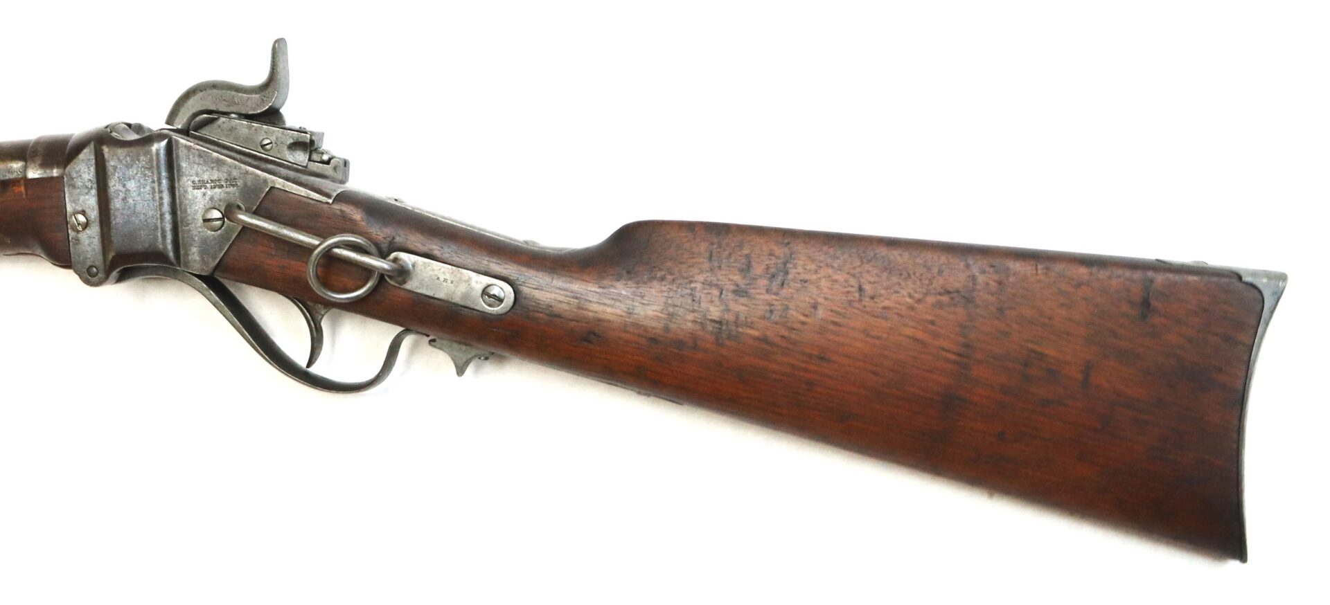 Close-up of the stock and receiver of an antique lever-action rifle with a wooden buttstock and metal hardware, photographed on a white background.