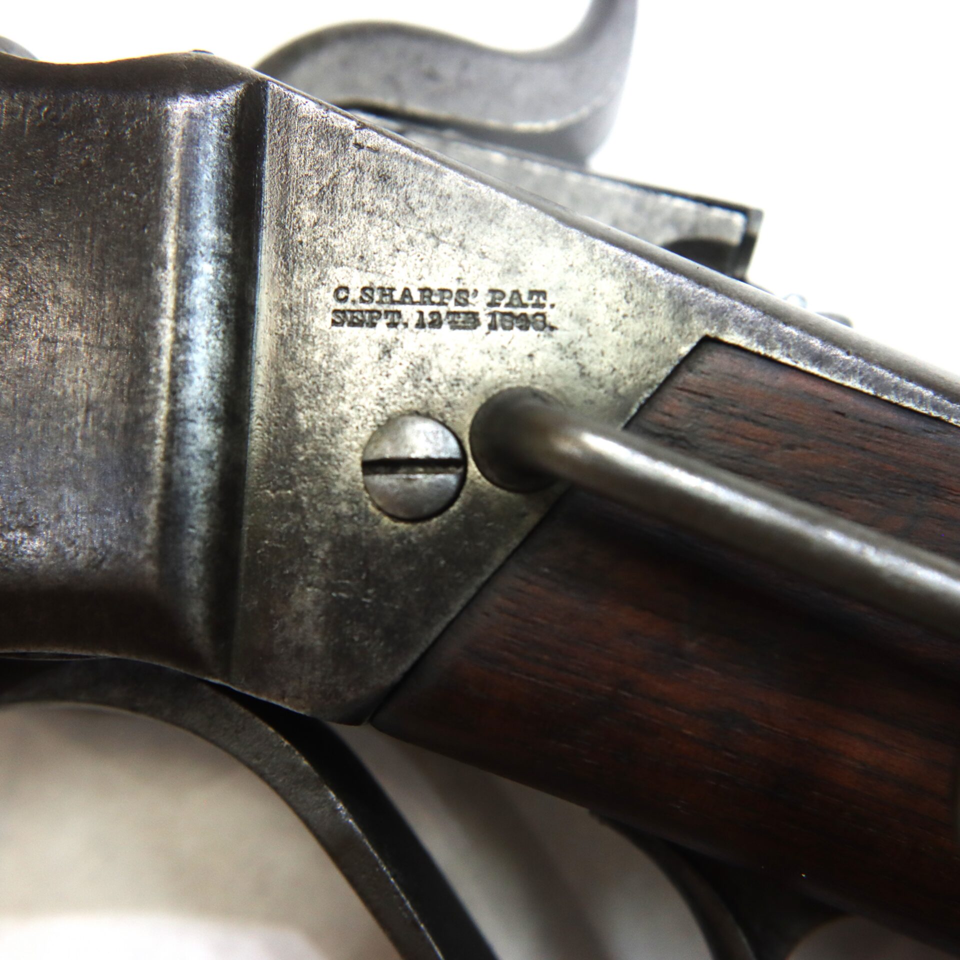 Close-up of a metal and wood firearm part, showing engraved text: "C. Sharps' Pat. Sept. 12th 1848" near a screw and lever mechanism.