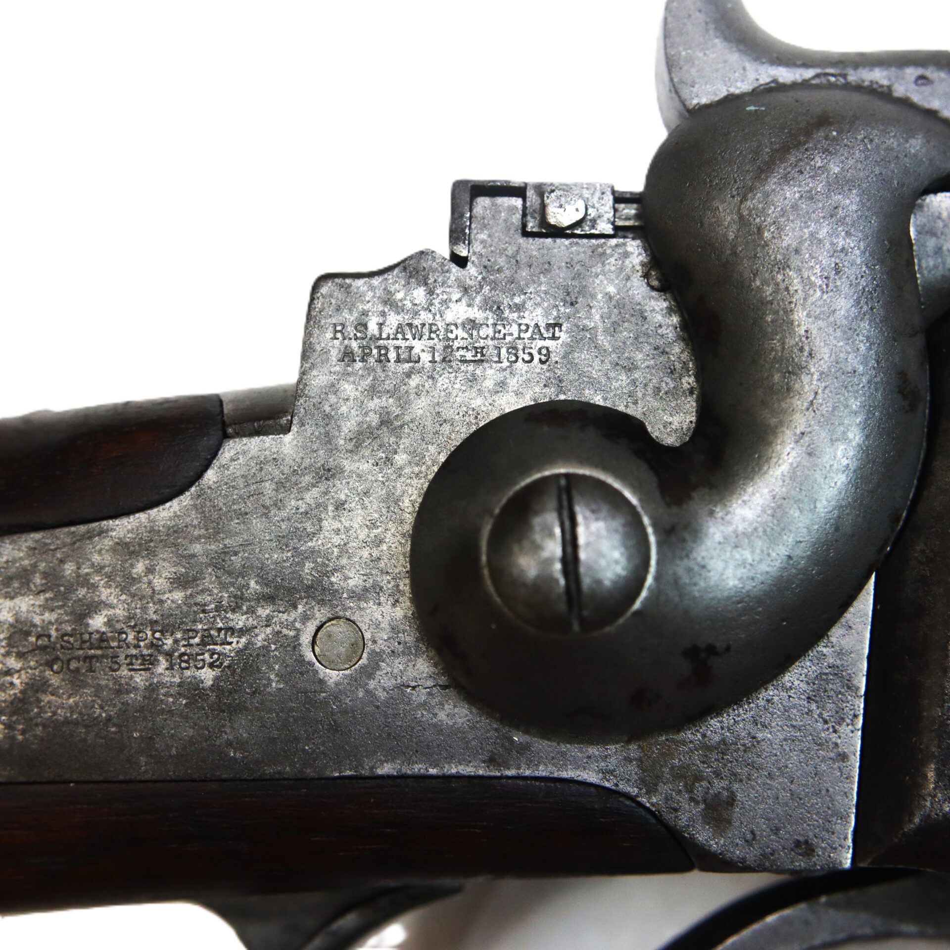 Close-up of a metal firearm receiver showing engraved patent dates and mechanical components, including a screw and lever.