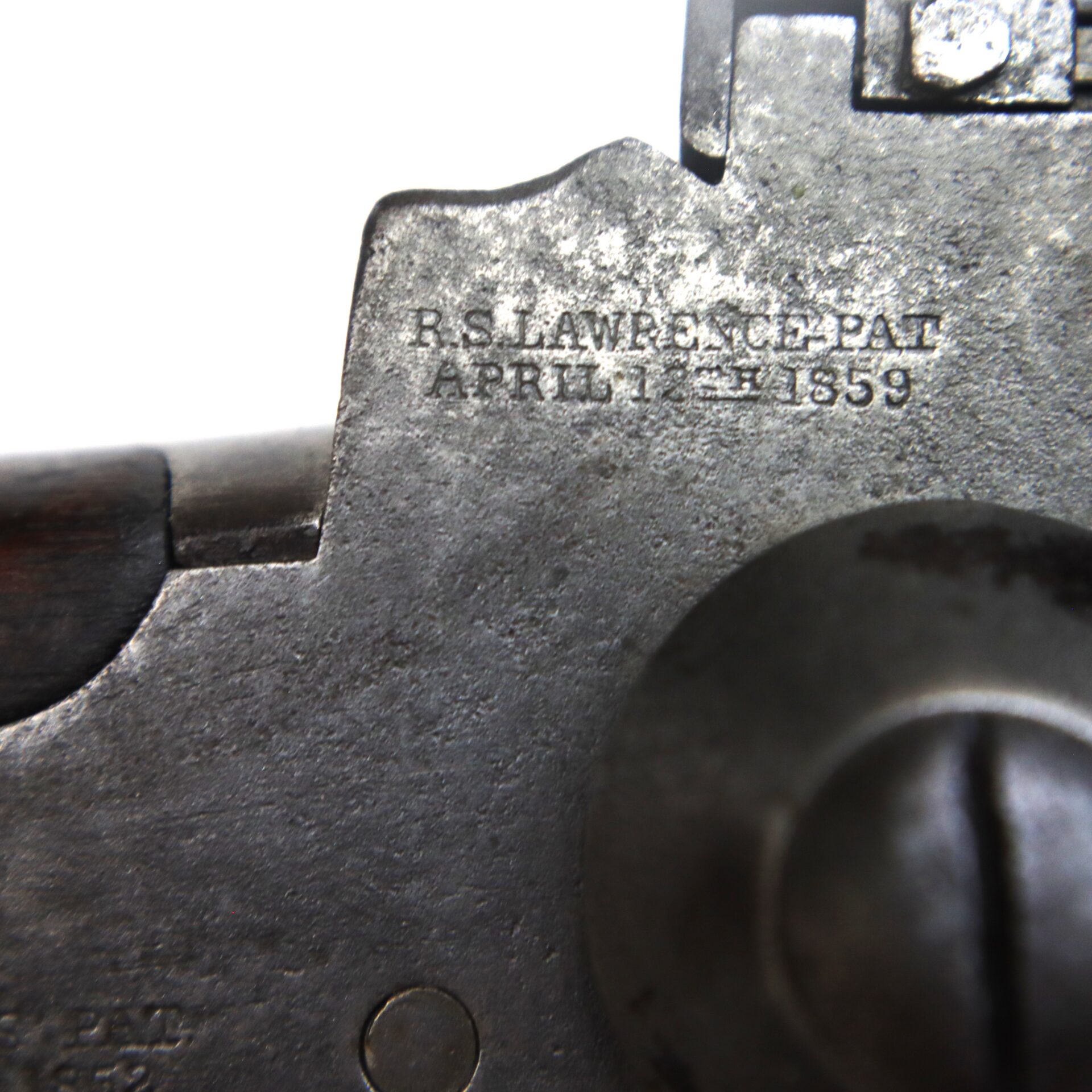 Close-up view of a metal surface with an engraved inscription reading "R.S. LAWRENCE PAT APRIL 12TH 1859.