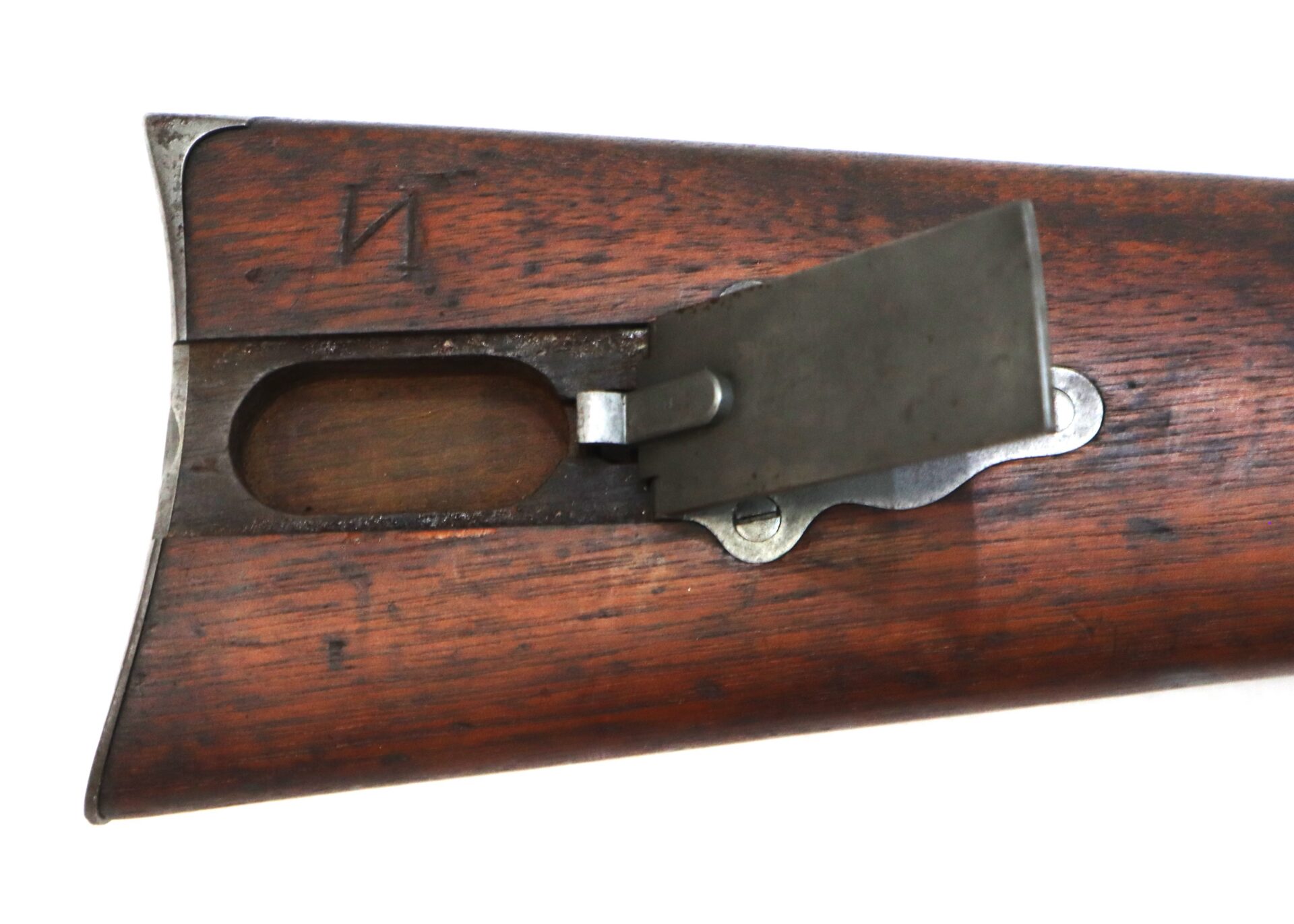 Close-up of a wooden rifle stock with a metal storage compartment door open, revealing an empty cavity inside.