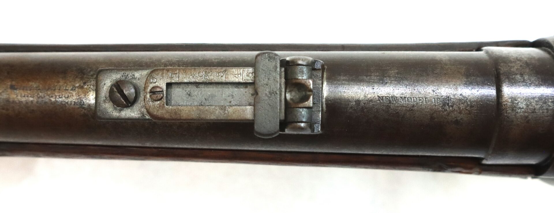 Close-up view of the rear sight and barrel markings on an old metal rifle, showing engraved text and worn metal surfaces.