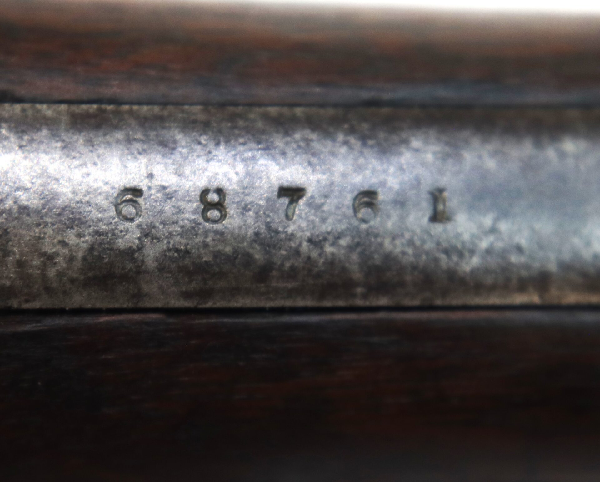 Close-up of a metal surface with the engraved serial number "68761" above a dark wooden background.