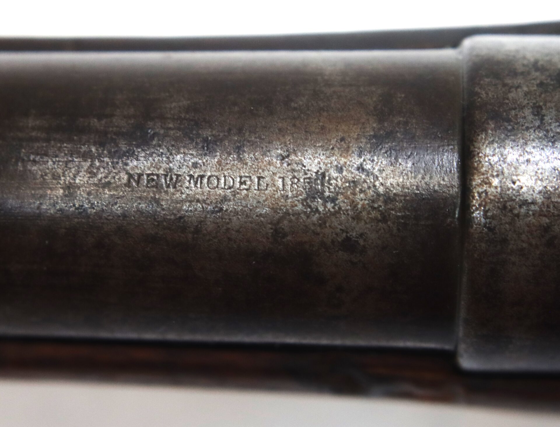 Close-up of a metal object with engraved text reading "NEW MODEL 1863" on a worn, slightly rusted surface.