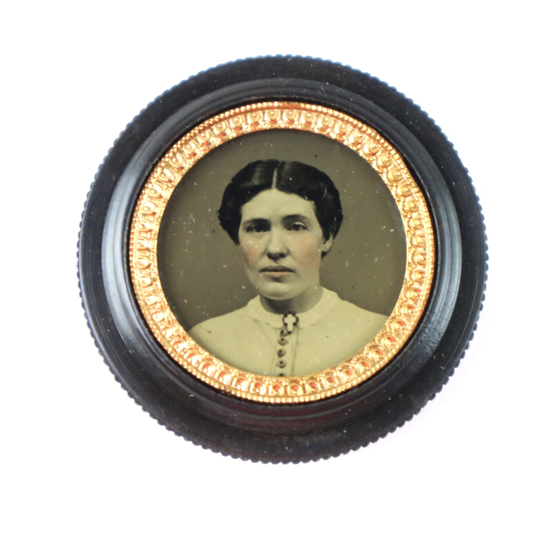 A vintage black-and-white portrait of a woman in a white blouse, set in a round, gold-trimmed black frame.