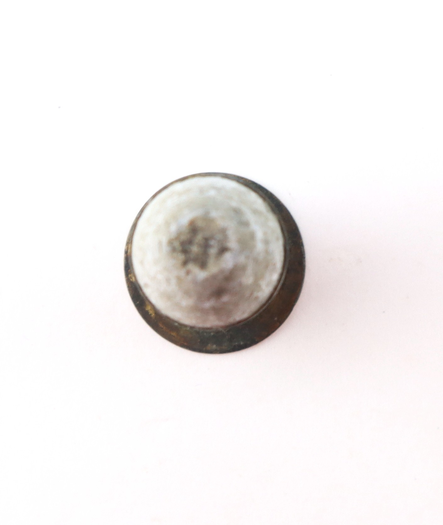 A round, dome-shaped metal object with a tarnished surface, viewed from above against a plain white background.