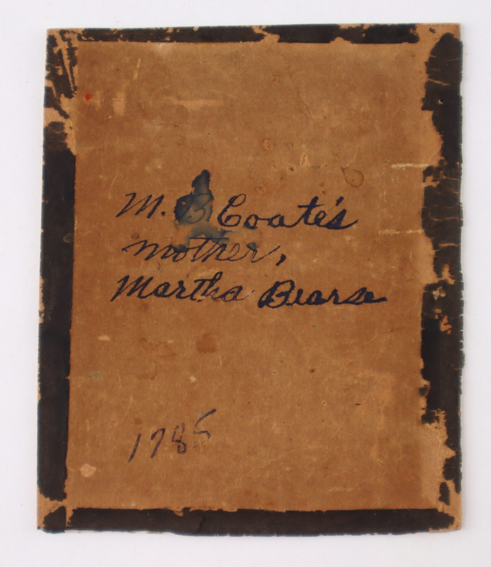 A worn, brown, rectangular piece of paper with black edges, handwritten text reads "Wm. D. Coate's mother, Martha Duera" and "1925.