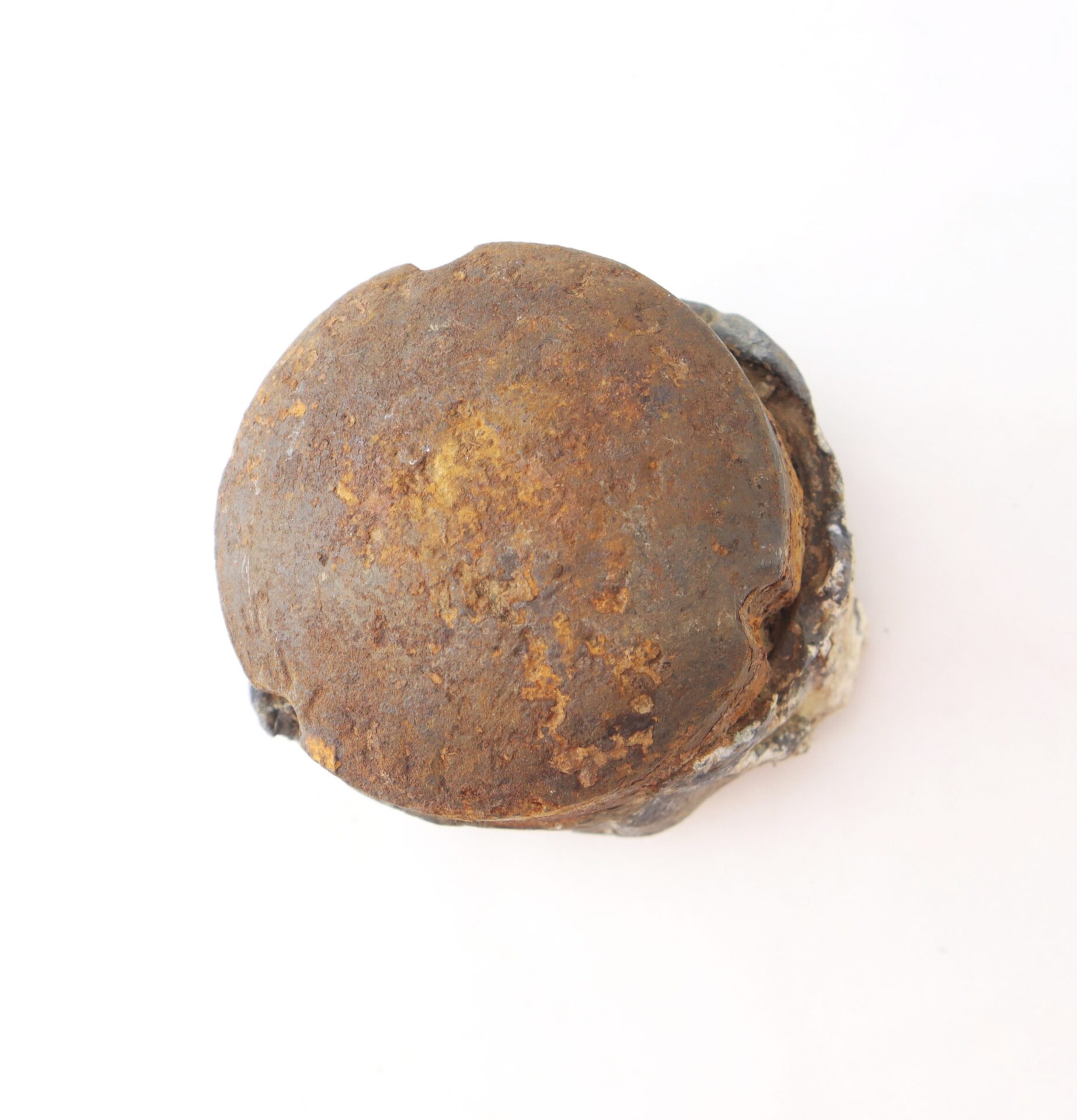 A rusty, round metal object with a flat top and weathered surface, sitting on a white background.