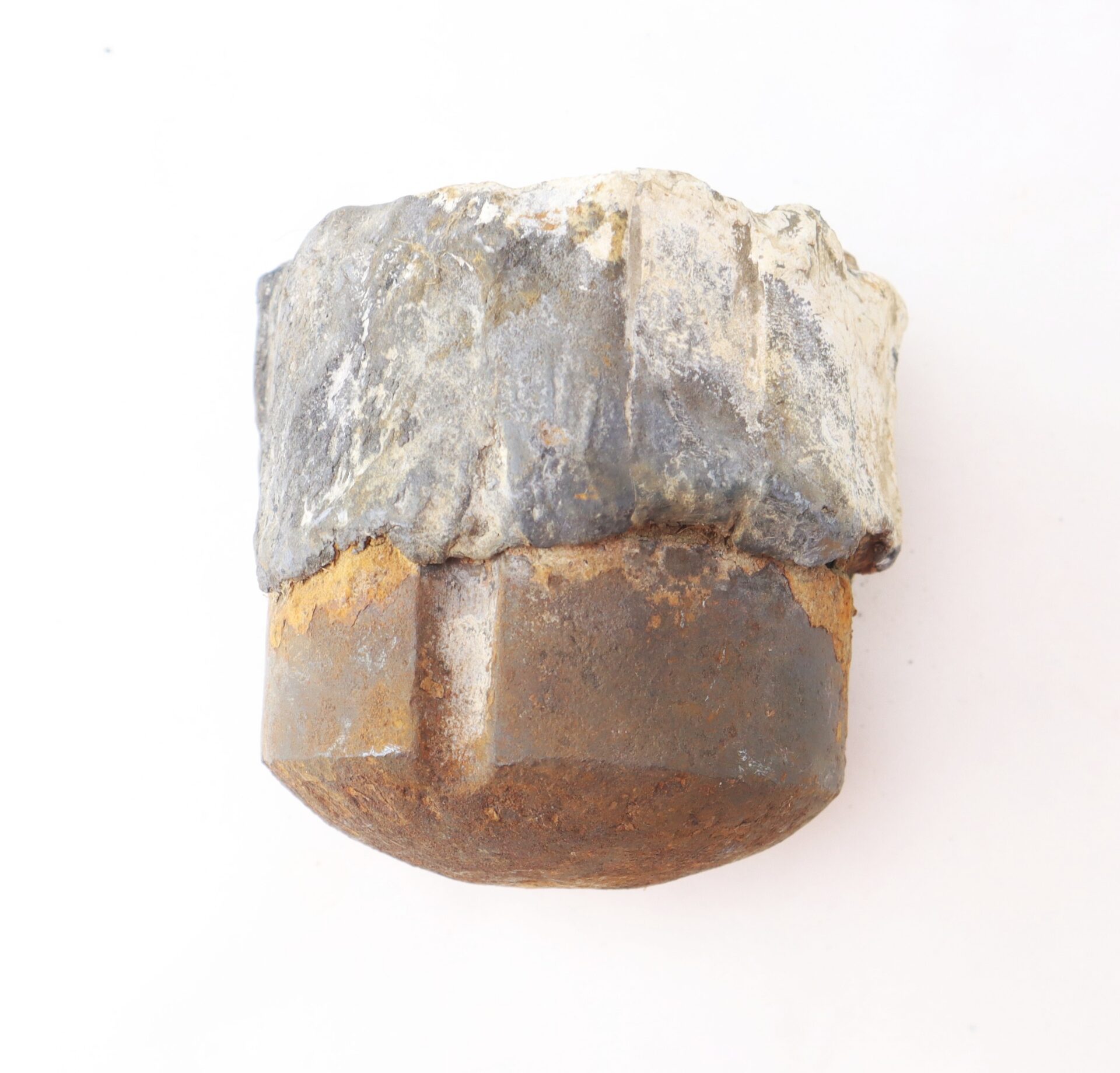 A close-up of a rusty metal bolt partially covered in a white and gray encrustation, set against a plain white background.