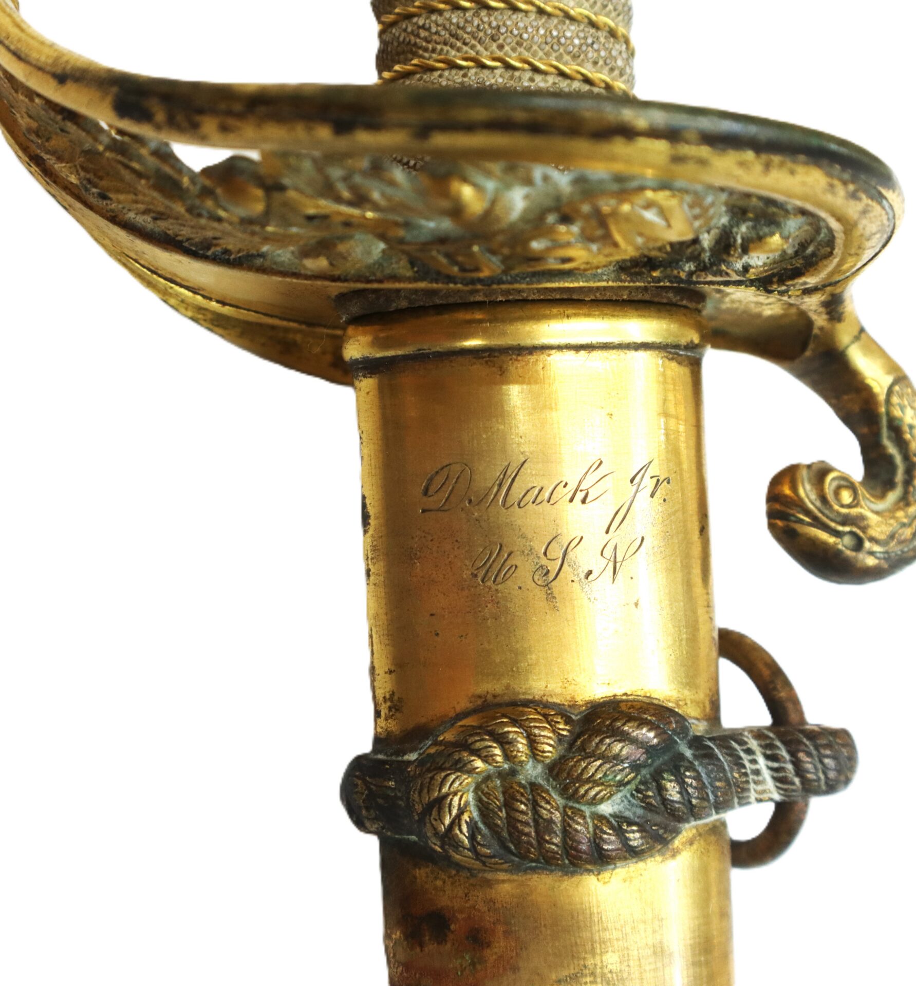Close-up of a brass sword hilt with ornate detailing and an engraved inscription reading "D. Mack Jr U.S.N.