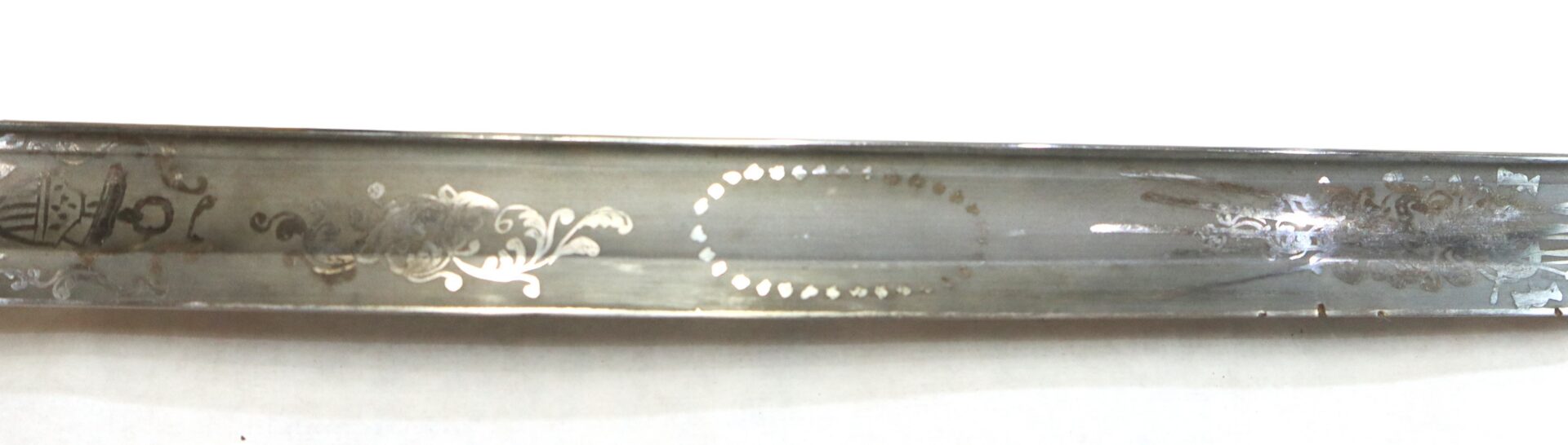 A close-up of a metal sword blade featuring intricate etched patterns and decorative designs along its surface.