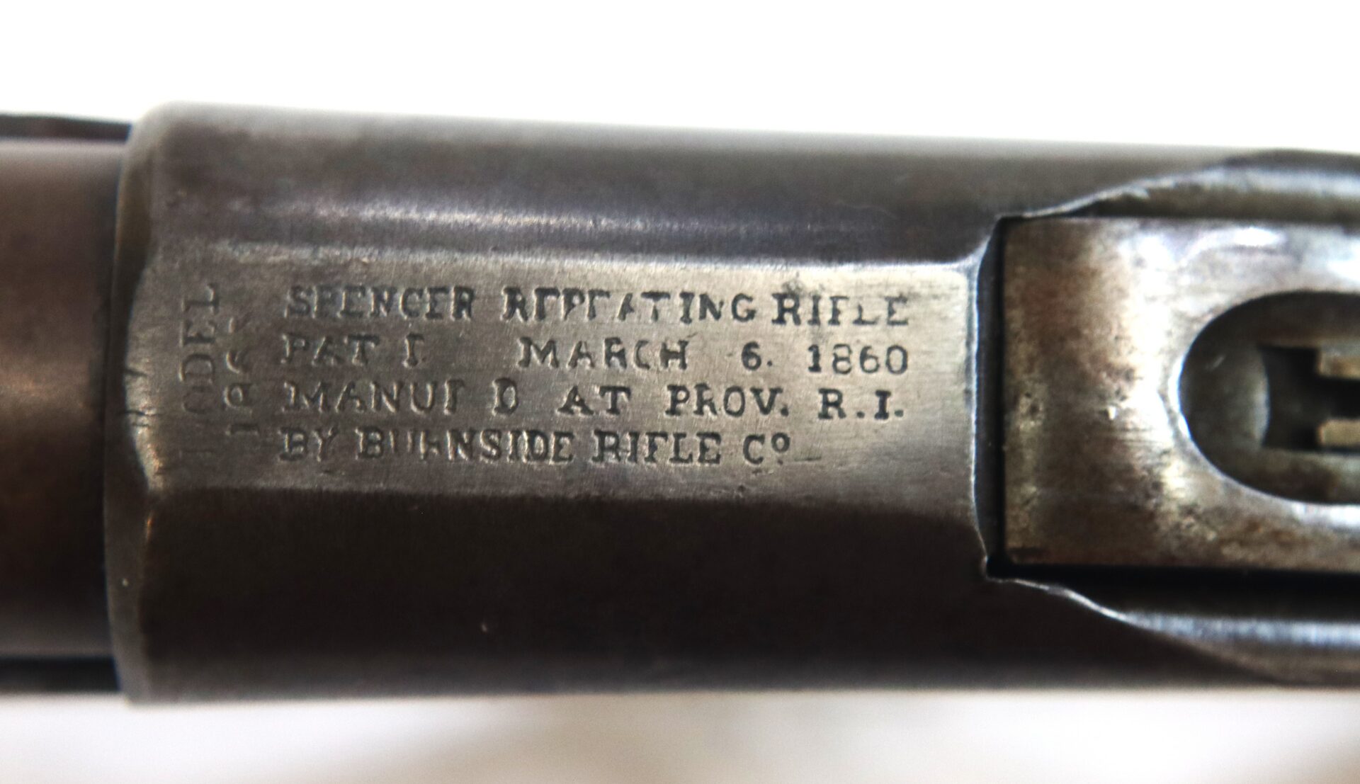 Close-up of a metal rifle barrel engraved with "Spencer Repeating Rifle, Pat’d March 6, 1860, Manu’d at Prov. R.I. by Burnside Rifle Co.