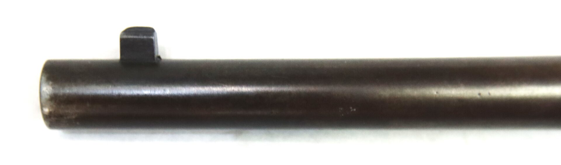 Close-up of the front sight on a dark metal gun barrel against a white background.