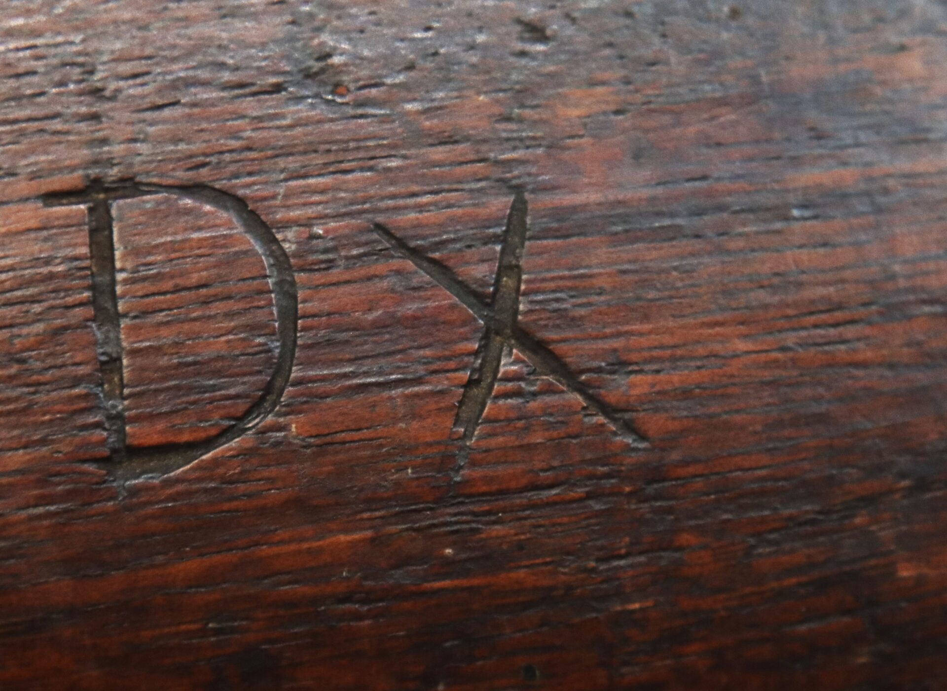The letters "DX" are carved into a dark wooden surface.