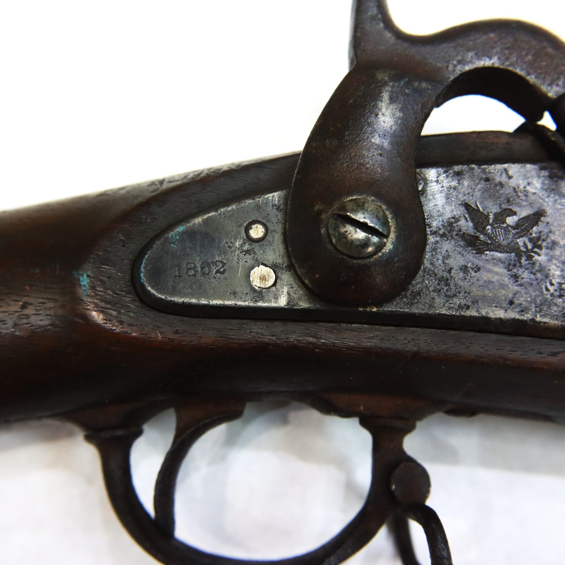 Close-up of an antique firearm trigger mechanism with visible engravings, including the year "1802" and an eagle emblem on the metal plate.