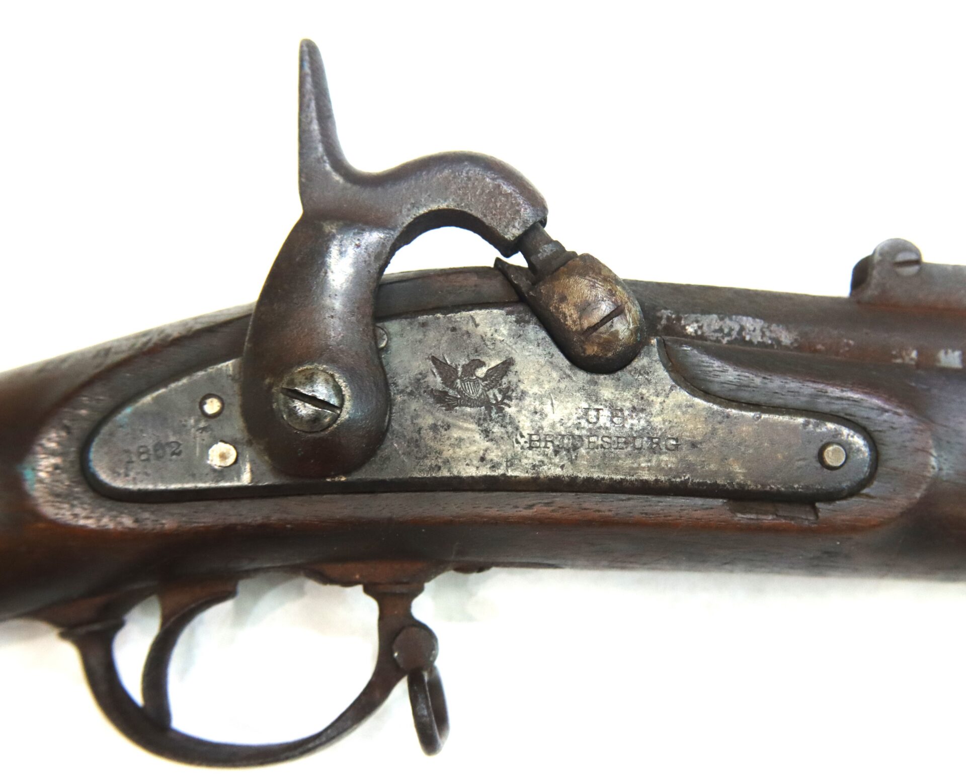 Close-up of the lock mechanism of an antique musket, showing a hammer, trigger, and engraved markings including an eagle and the year 1862.