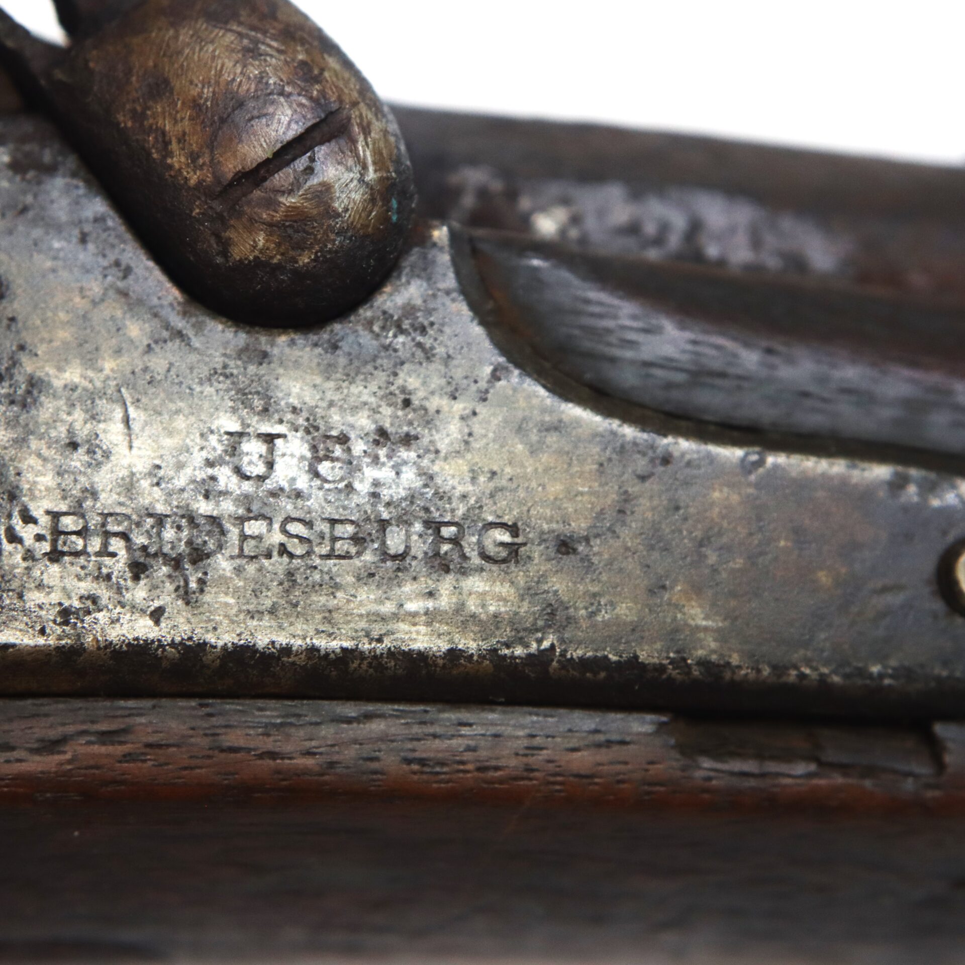Close-up of a metal rifle receiver stamped with "U.S." and "BRIDESBURG," showing signs of wear and patina.