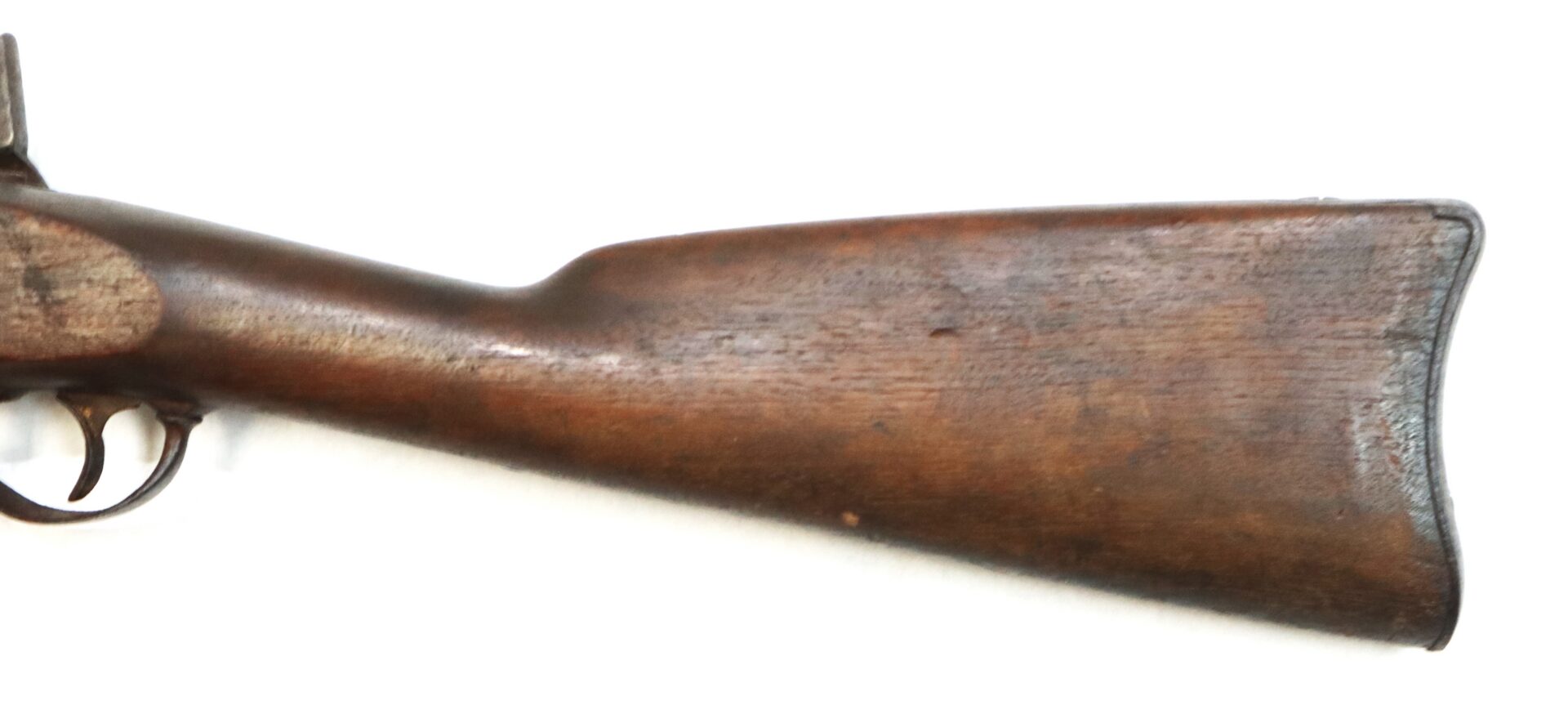 Close-up of the wooden stock and trigger of an antique rifle.
