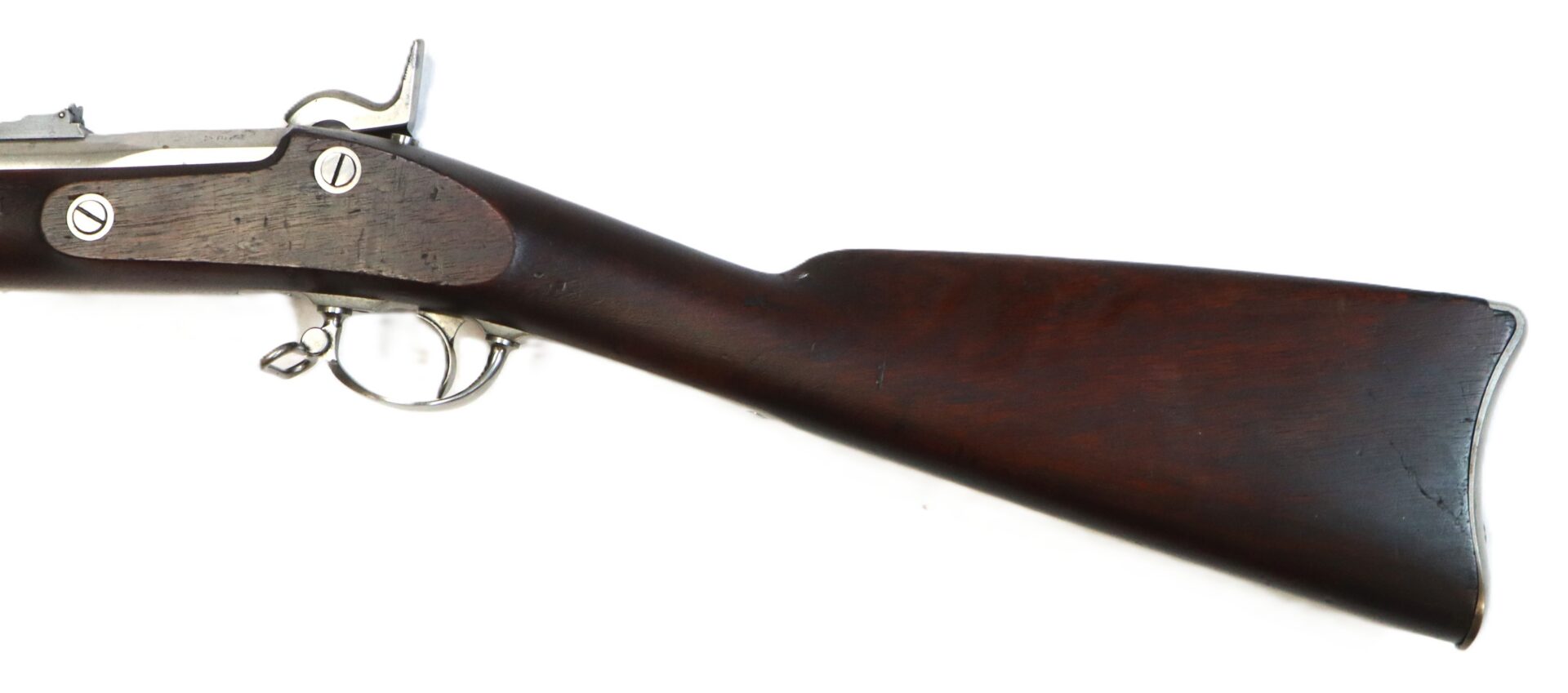 Side view of a dark wooden rifle stock with attached metal trigger guard and partial sight of the action mechanism.