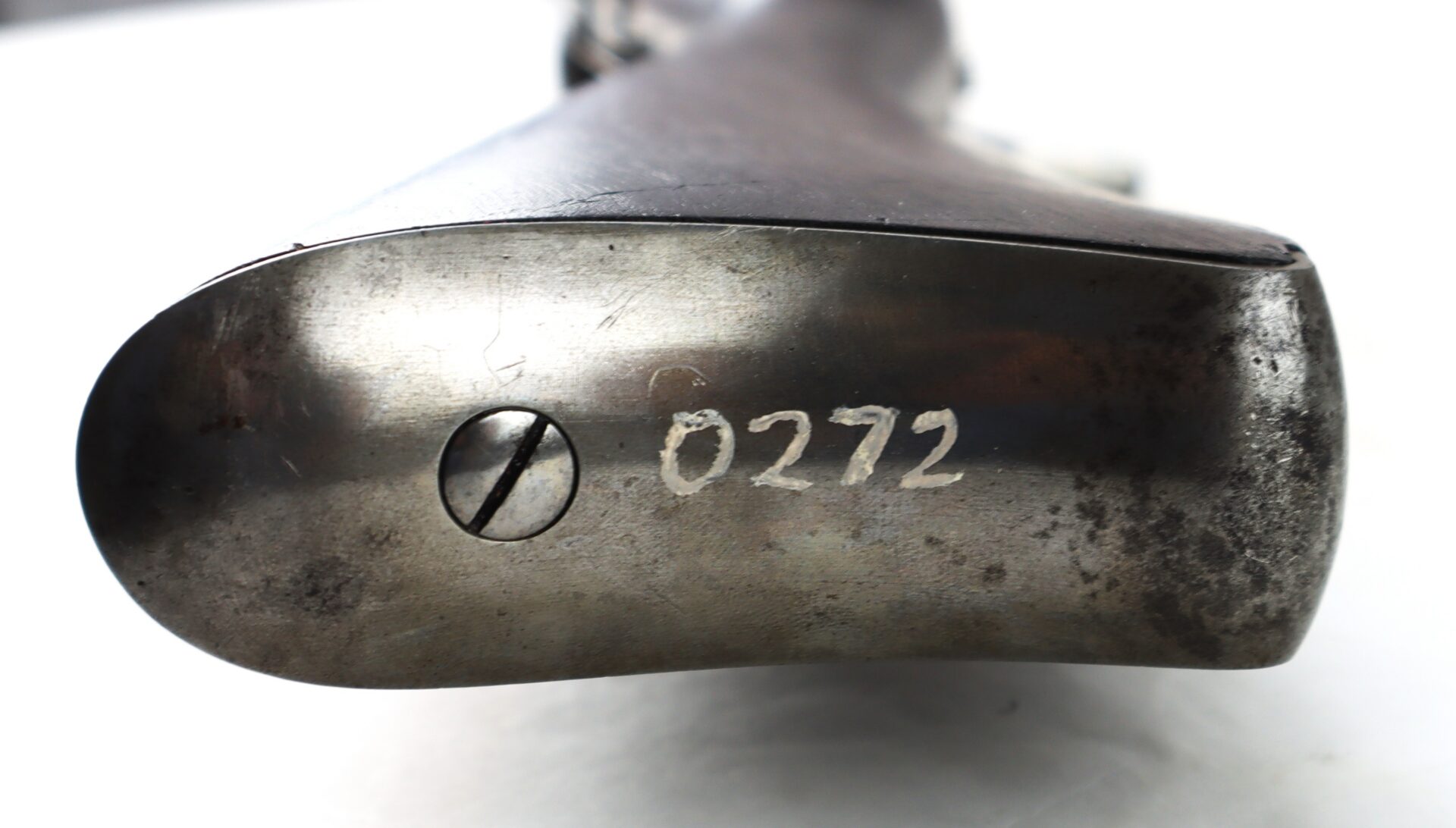 Close-up of a metallic gun butt plate with a screw and the number "0272" marked on it, showing signs of wear and scratches.