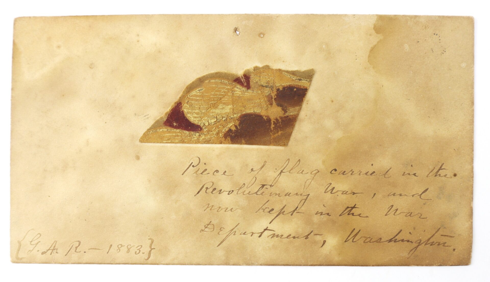 A small fragment from a Revolutionary War flag, accompanied by stained paper with handwritten text attesting that it was carried during the war and preserved in the War Department, Washington, is offered as the Revolutionary War Flag Fragment with Exceptional 1883 Provenance.
