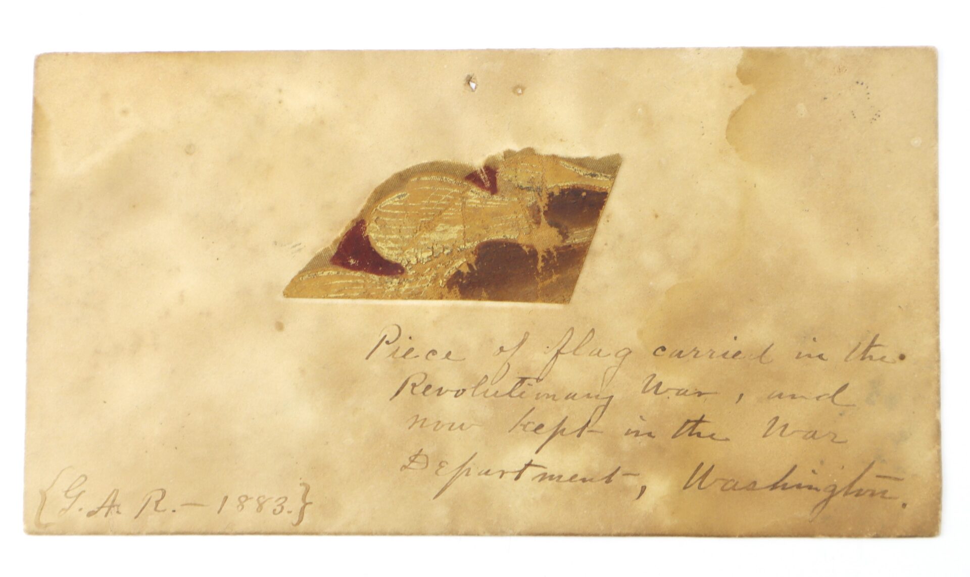 Revolutionary War Flag Fragment with Exceptional 1883 Provenance, mounted on stained paper inscribed as a relic of the Revolutionary War and once housed in the War Department, Washington.