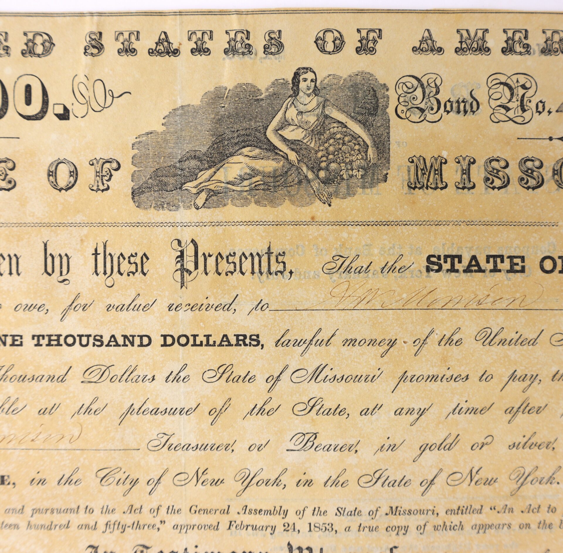 A vintage Missouri bond certificate shows an illustration of a woman with a cornucopia, ornate lettering, signatures, and fine print detailing its legal and financial terms.