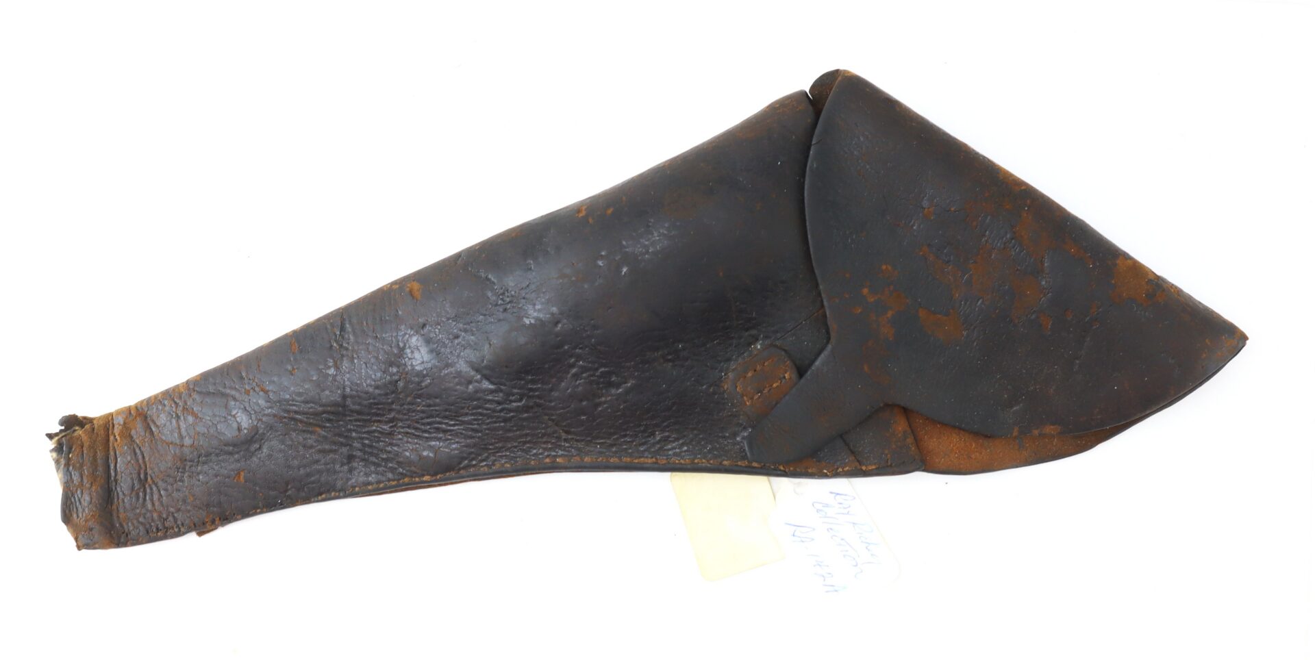 Worn, dark brown leather holster with a flap cover, showing signs of age and surface wear, lying flat on a white background with a small slip of paper partially underneath.