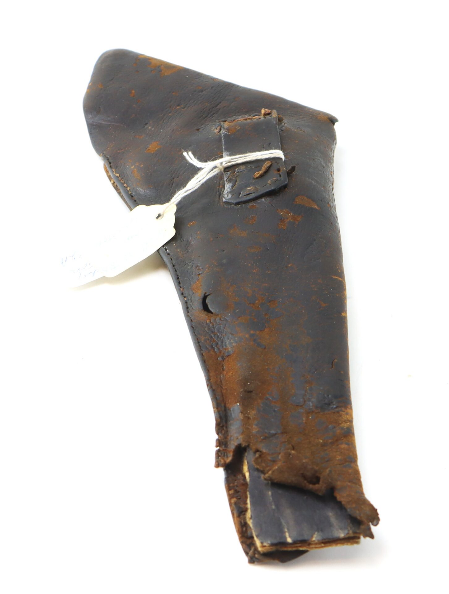 Worn, brown leather gun holster with visible rust and damage, featuring a small strap and a tied white tag, photographed on a white background.