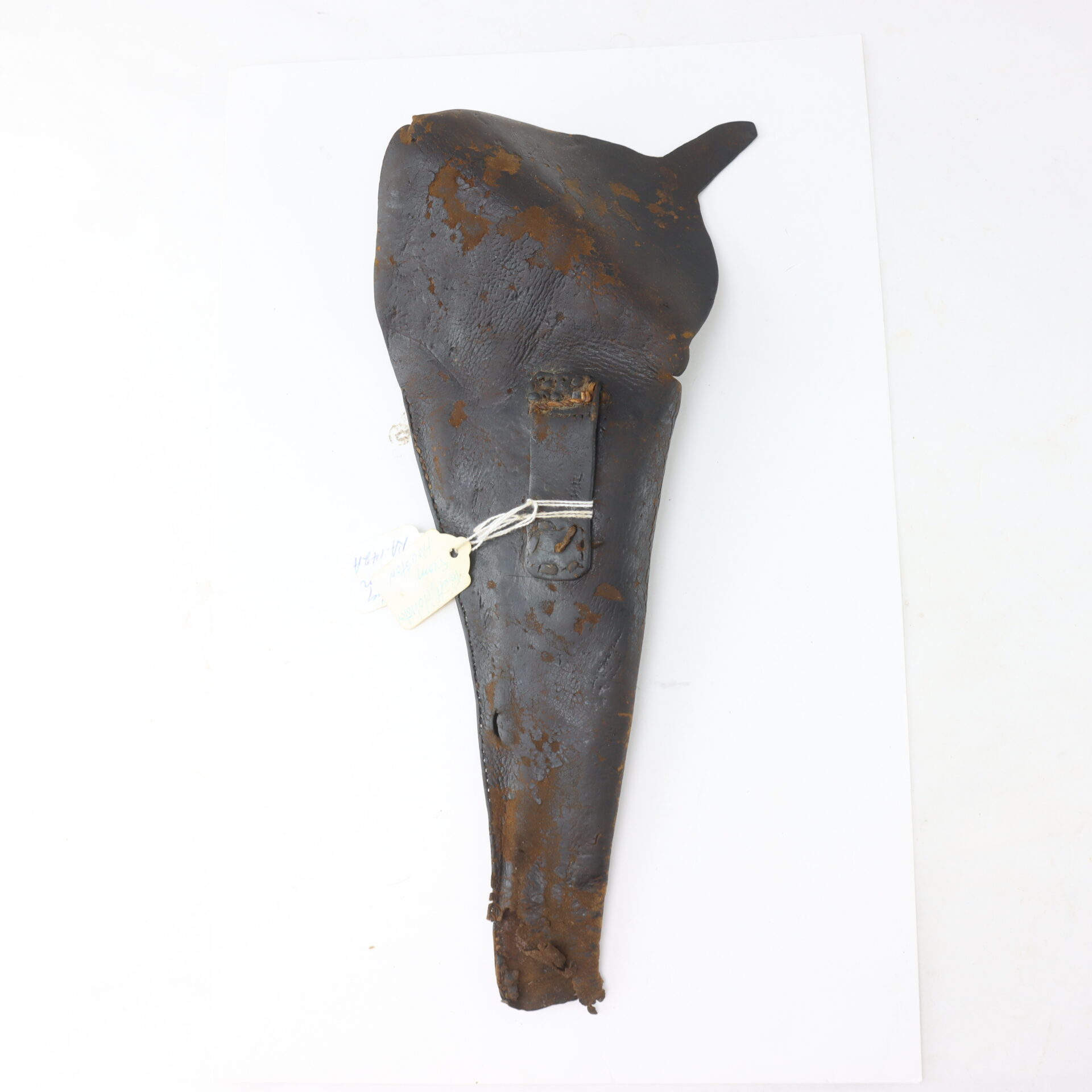 Weathered, rusted metal object shaped like a holster with a clasp, tag, and chain attached, displayed on a white background.