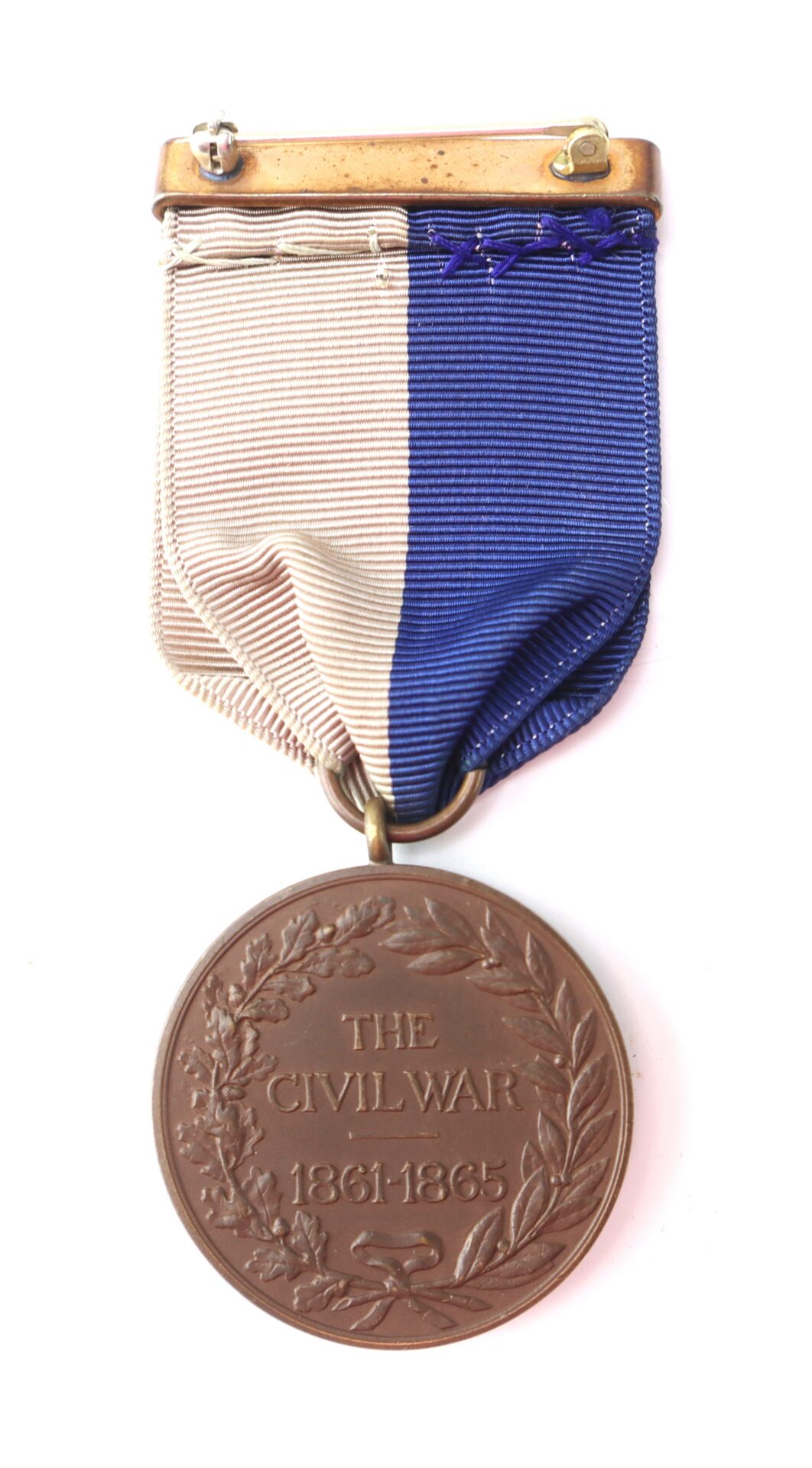 Bronze Civil War medal with blue and beige ribbon, inscribed “The Civil War 1861-1865” surrounded by a laurel wreath.