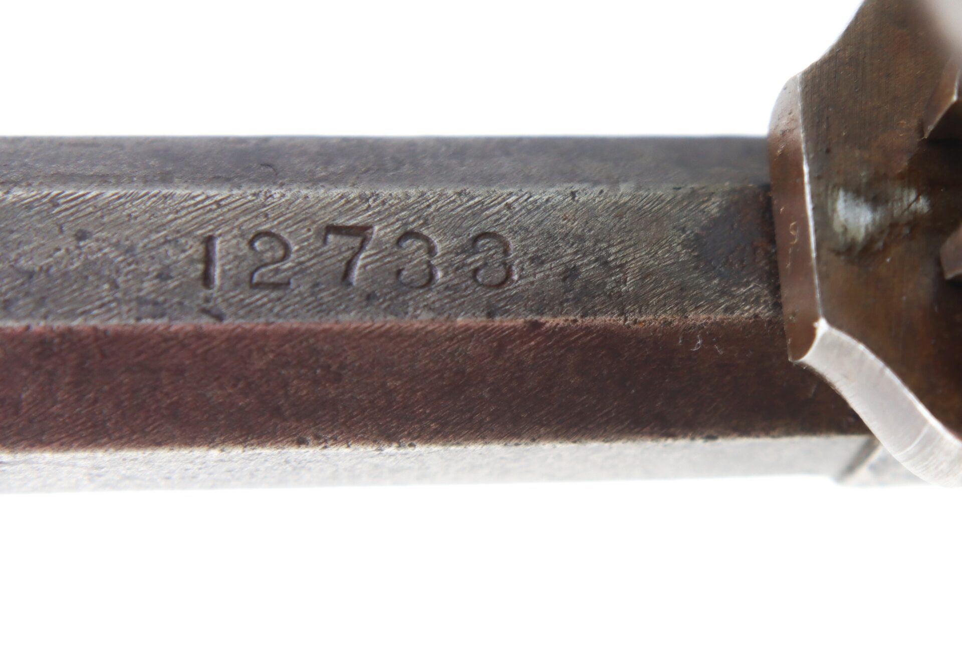Close-up of a metal object with the engraved number “12733” visible on its surface.