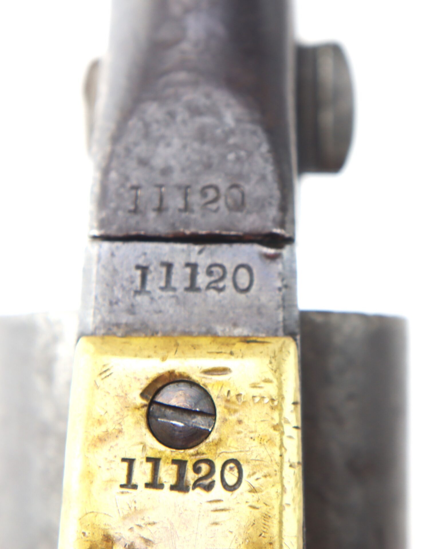 Close-up view of a metal object with the number 11120 stamped three times on different parts, including a brass section with a visible screw.