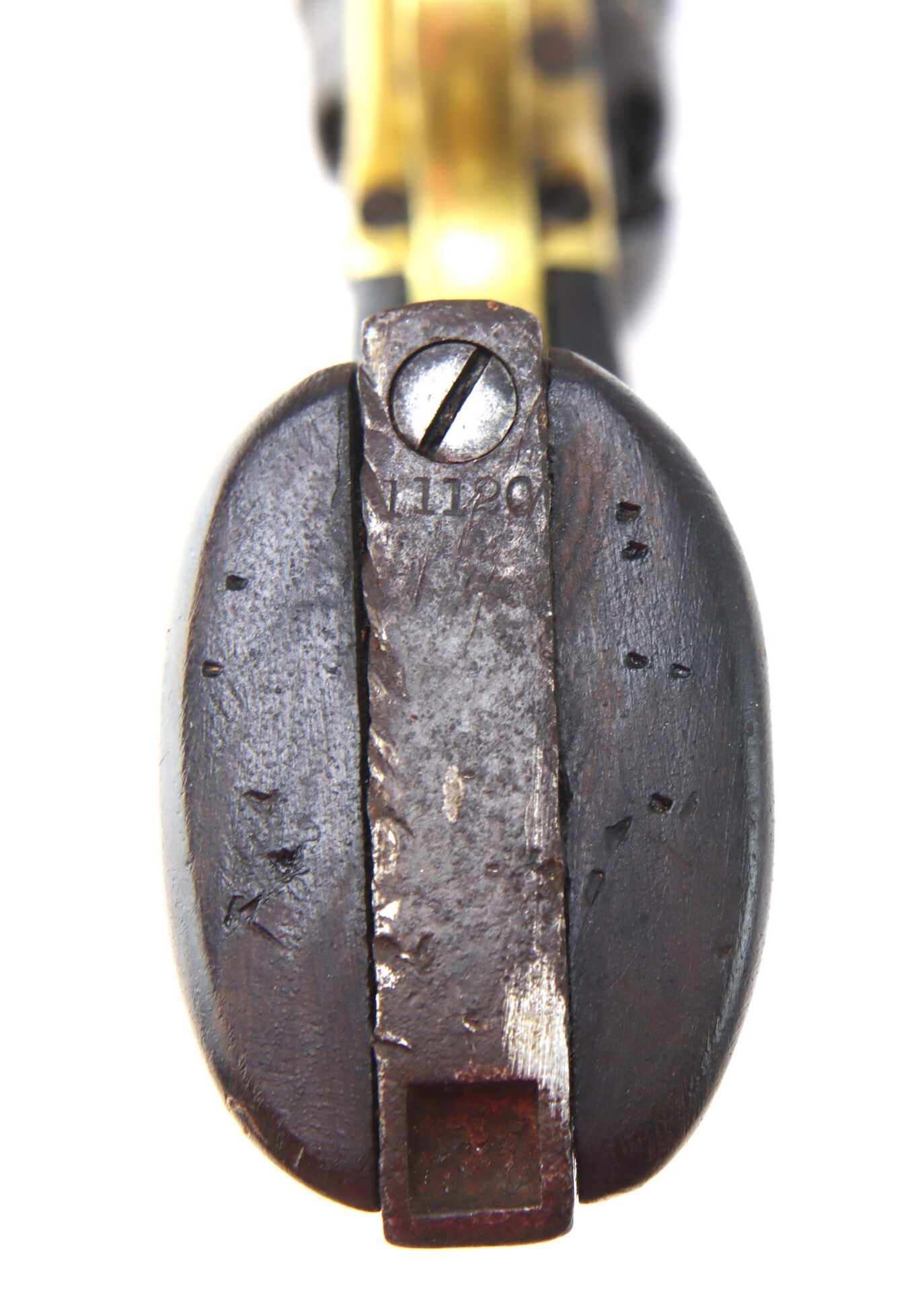 Close-up view of the grip and backstrap of an old revolver, showing a worn screw and markings on the metal parts.