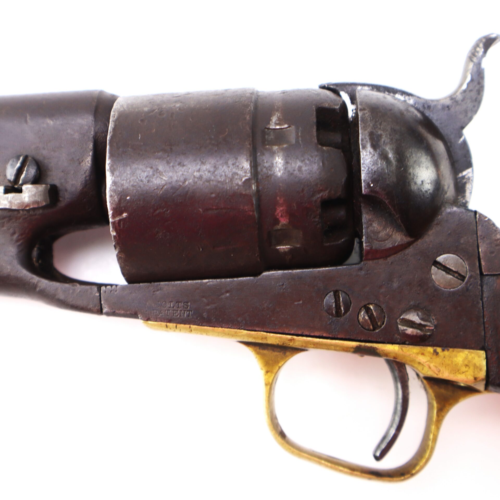 Close-up of the cylinder, trigger, and part of the barrel of an antique revolver with metal and brass components.