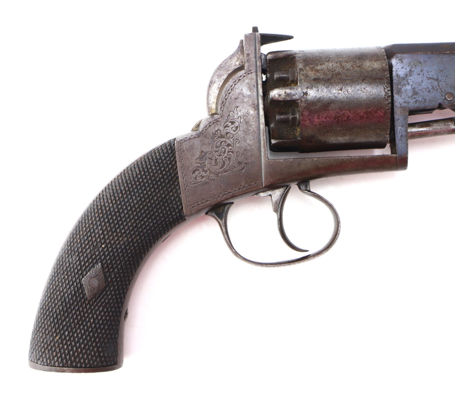 Close-up view of the handle, trigger, and cylinder of an antique revolver with ornate engravings on the metal and a textured grip.