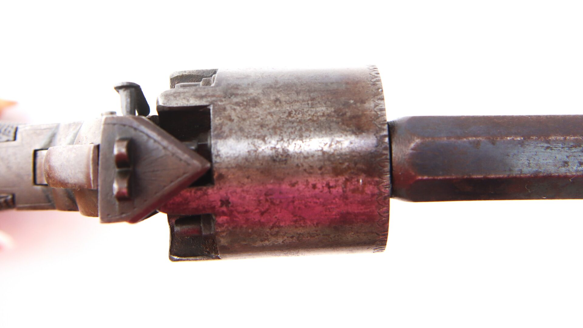 Close-up view of the cylinder and part of the barrel of an old, worn revolver against a white background.
