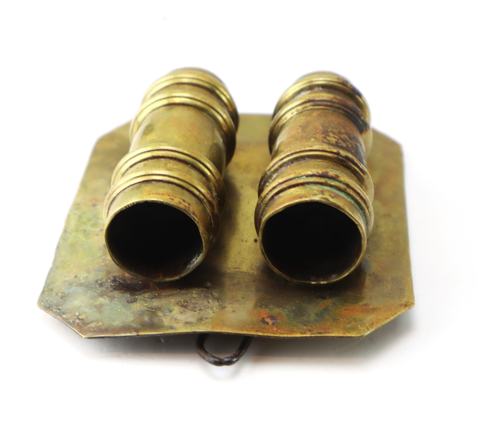 A pair of antique brass binocular eyepieces mounted on a tarnished rectangular metal plate with visible wear.