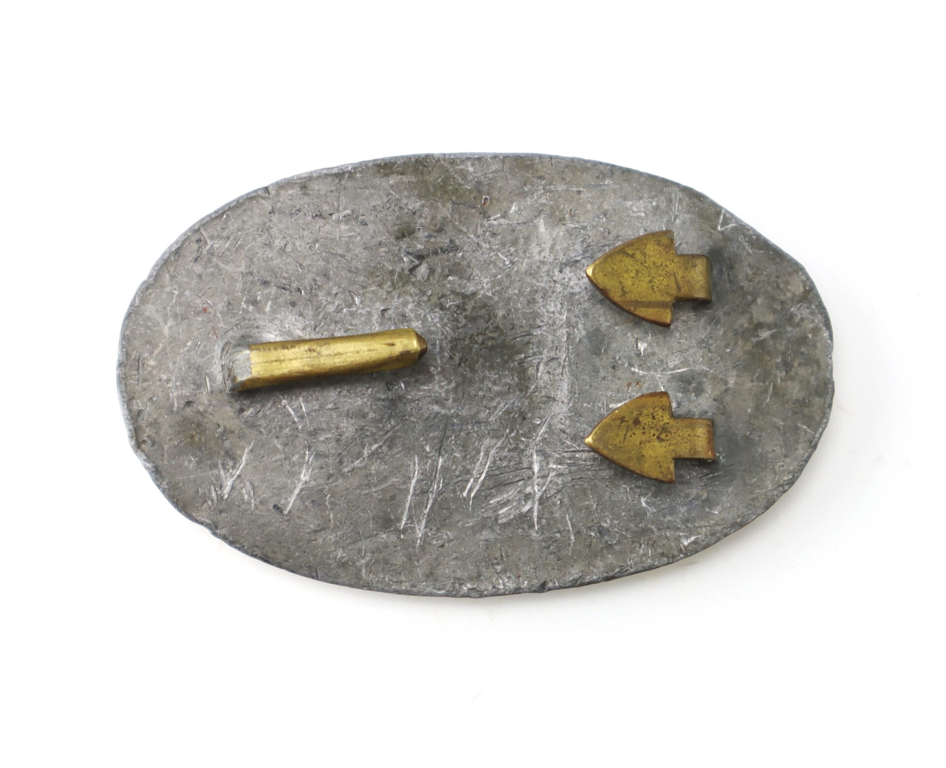 A roughly oval, flat metal object with two gold arrow-shaped pieces and one gold bar attached to its surface.