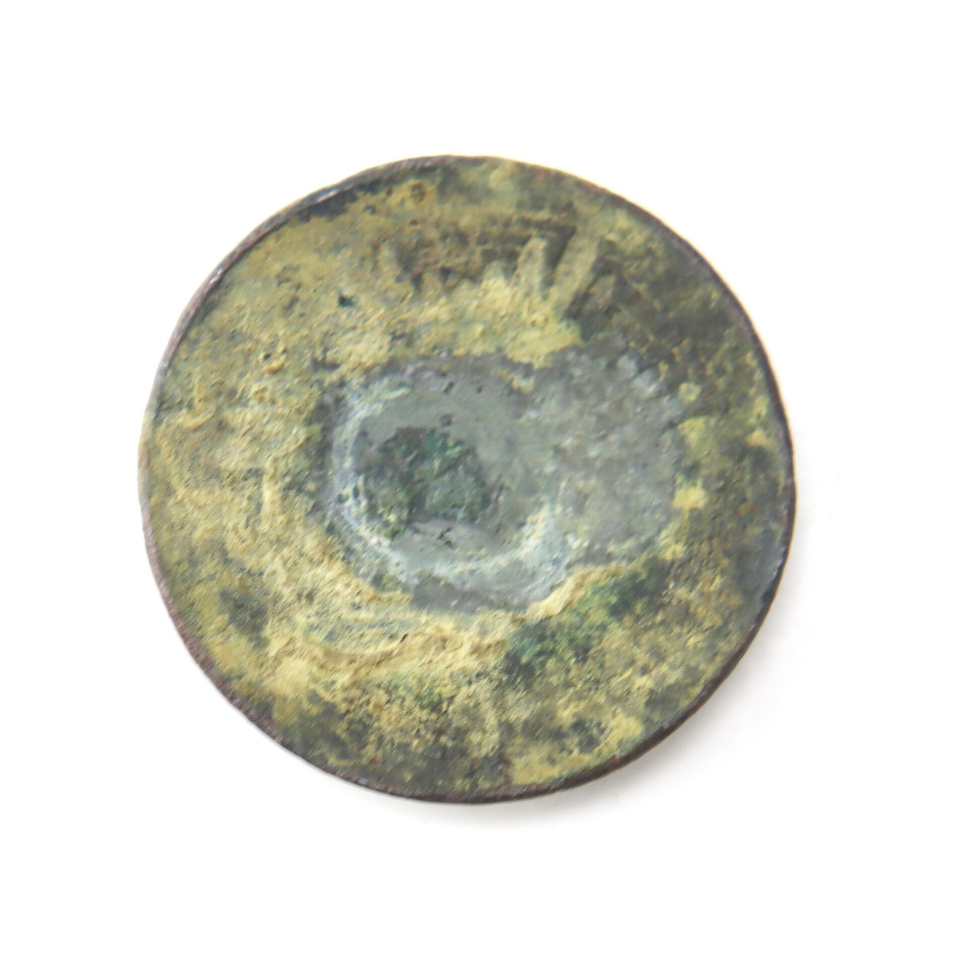 A heavily corroded and worn round metal object, possibly an old coin, displayed on a white background.