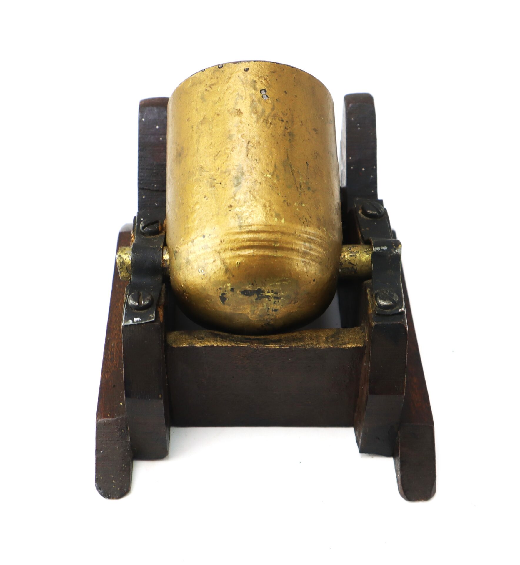 Brass model cannon with a wooden base, viewed from the front, showing the barrel and mountings.