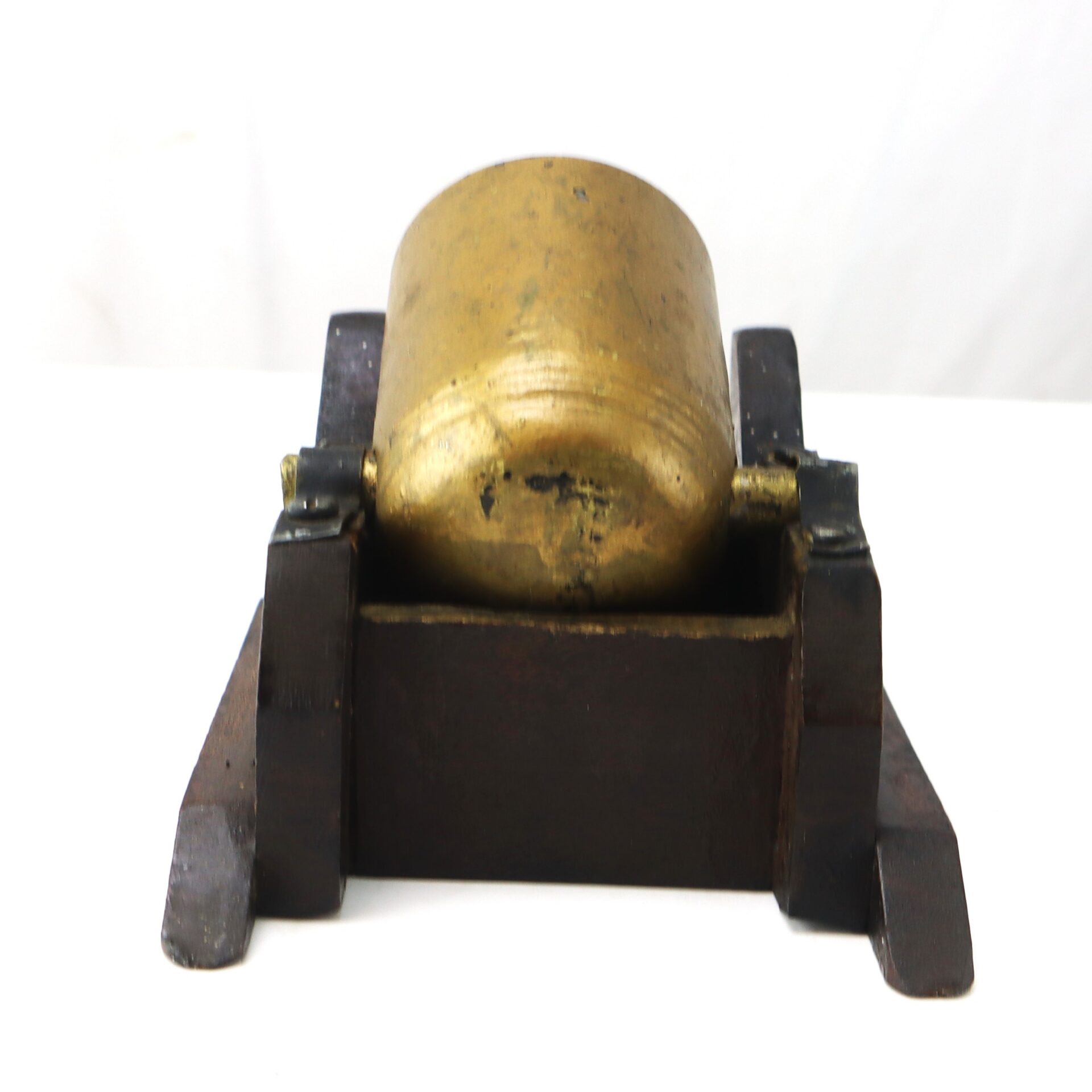 A brass cannon model mounted on a dark wooden base, viewed from the front against a white background.