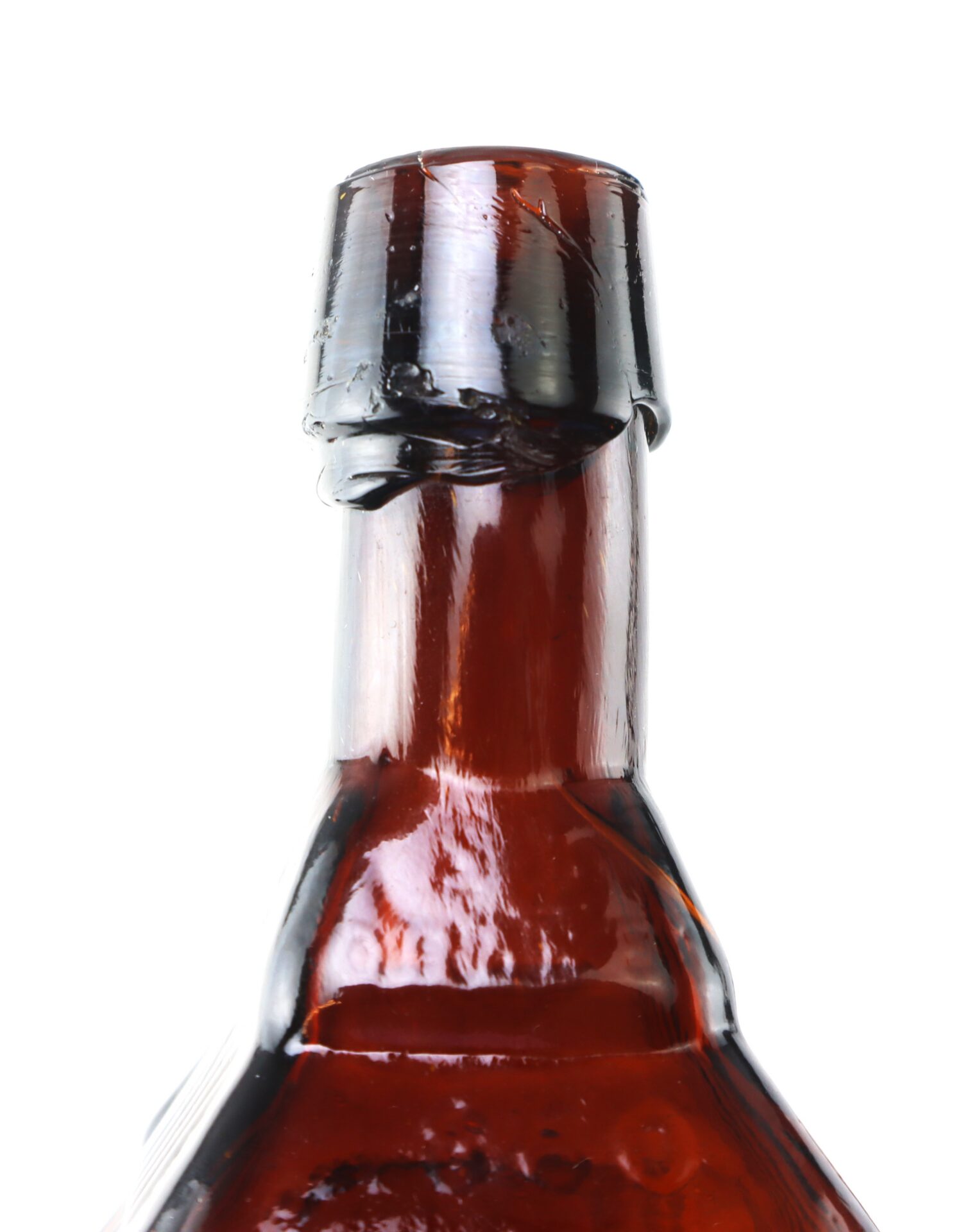 Close-up of the neck and cap of an amber glass bottle with a wax seal, photographed against a white background.