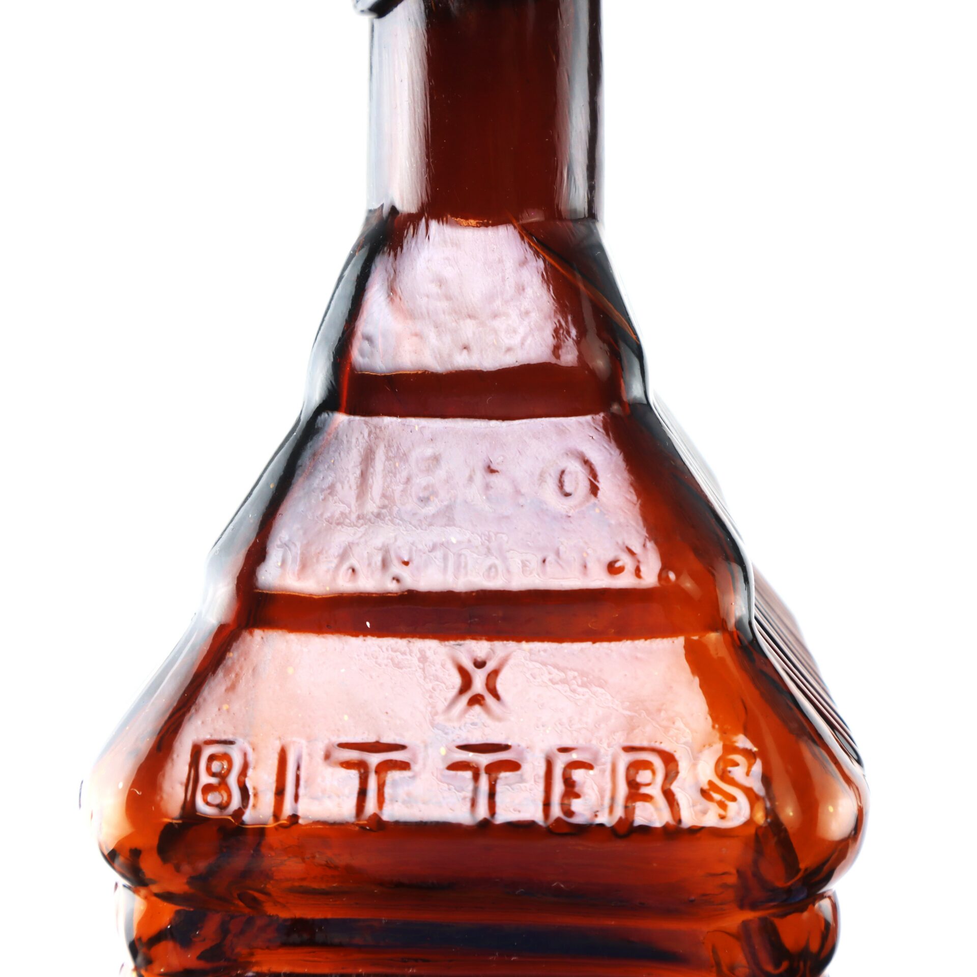 Close-up of a vintage amber glass bottle with the word “BITTERS” embossed on it, set against a white background.