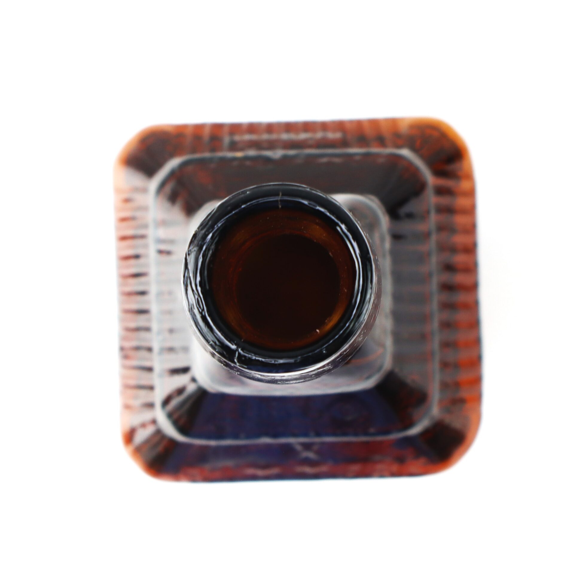 Top-down view of an open, square-shaped brown glass bottle against a white background.