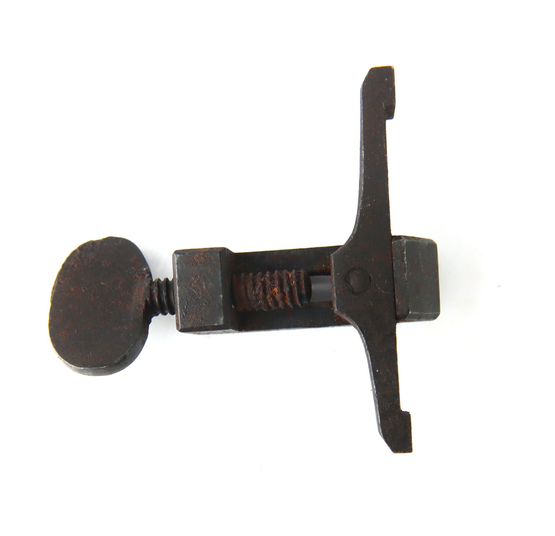 A rusty metal tool with a flat knob handle and adjustable screw mechanism, photographed on a white background.