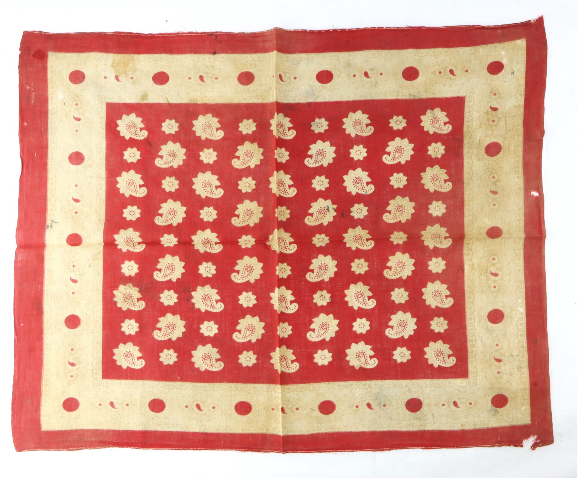 Square red cloth with a gold border, decorated with a grid of gold floral patterns in the center and gold dots around the edges. The fabric appears slightly wrinkled.