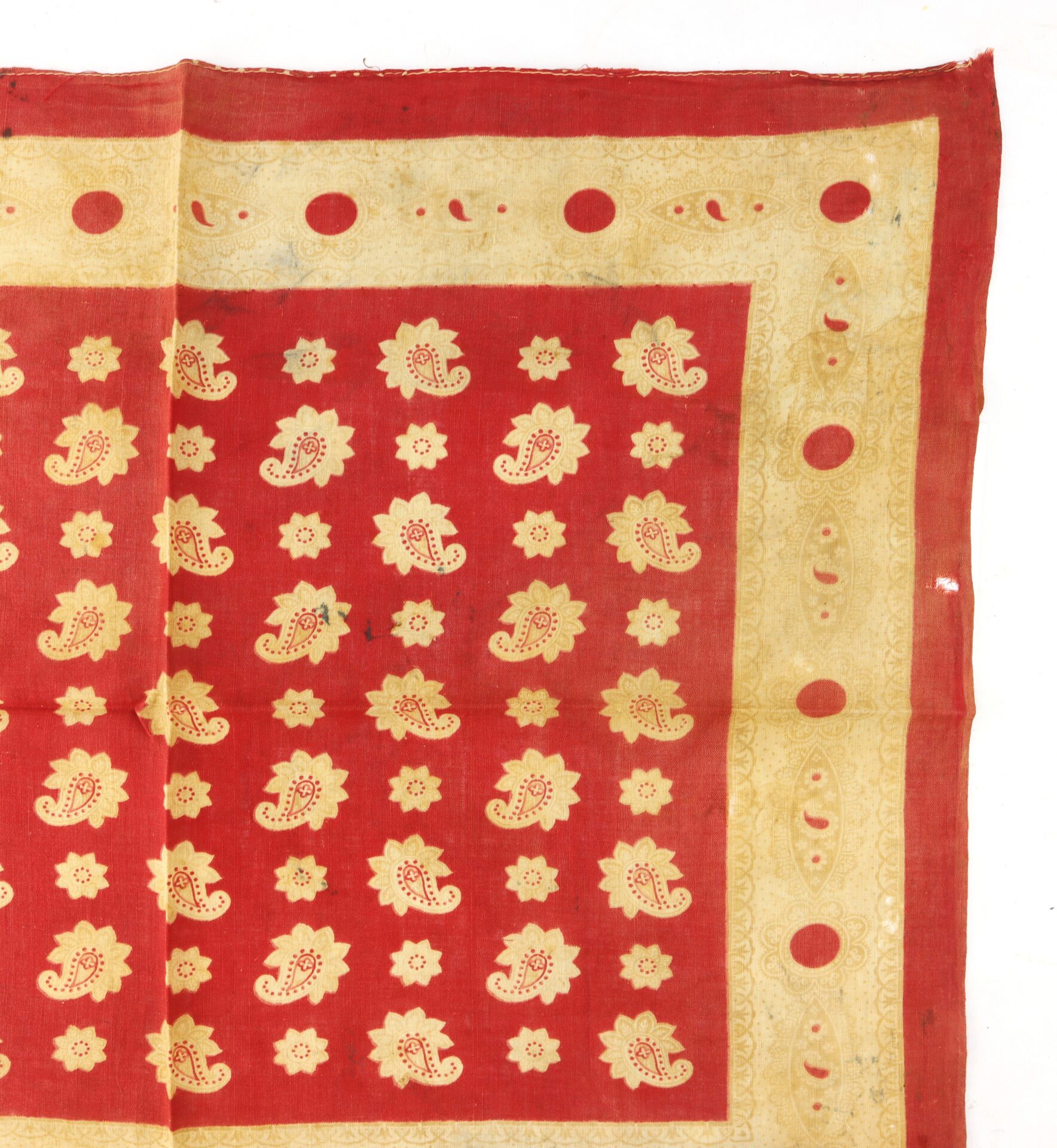 Red and yellow textile with a repeating paisley and floral pattern in the center and a decorative border featuring geometric and floral motifs.
