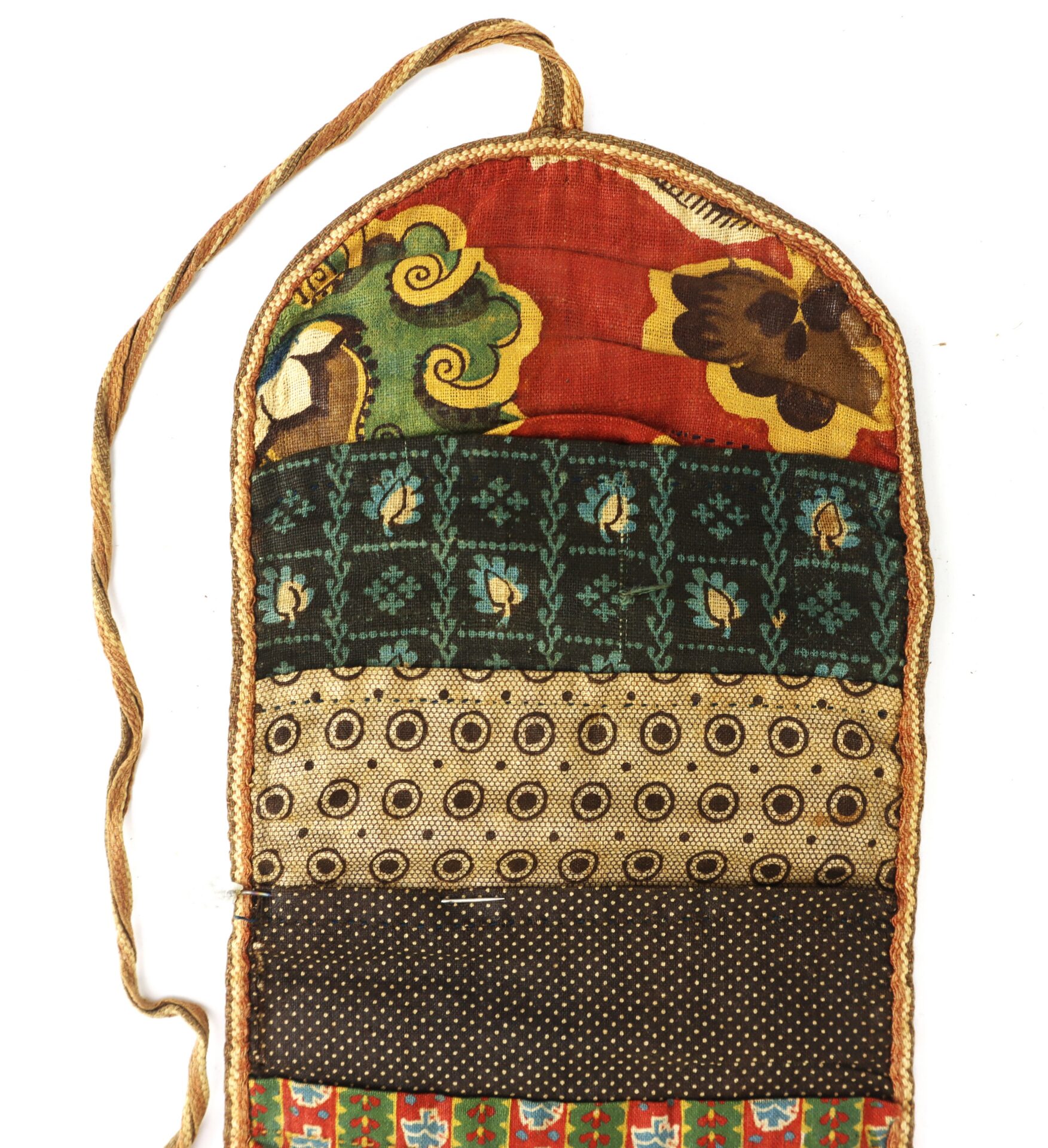 A fabric pouch with a tie string, featuring horizontal bands of various colorful patterns including floral, geometric, and polka dot designs.